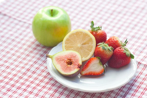 Jabłko, cytryna, fig i truskawki na talerzu — Zdjęcie stockowe
