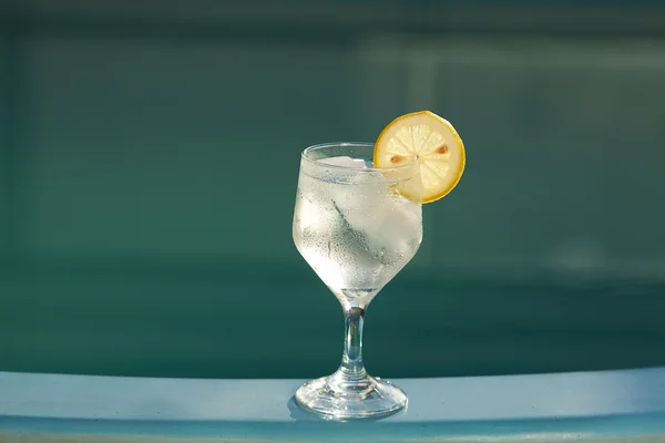 Swimming pool and a wine glass with ice and lemon — Stock Photo, Image