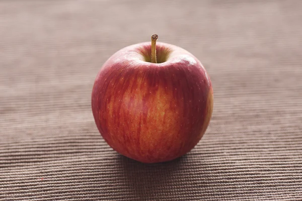 Яблоко лежит на коричневом коврике — стоковое фото