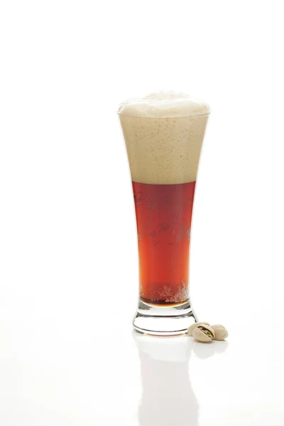 Темное пиво с пеной в высоком стакане и фисташки изолированы — стоковое фото