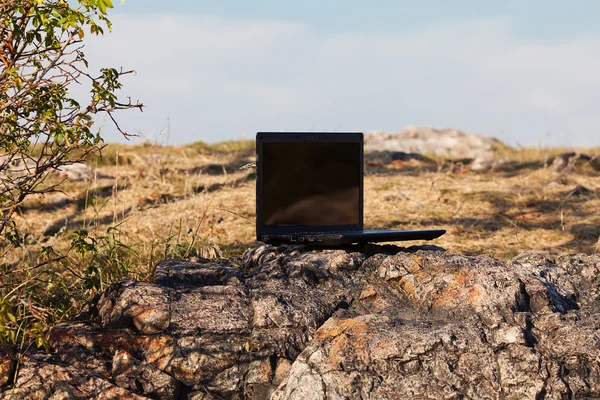 Laptop fica em uma rocha contra o céu azul — Fotografia de Stock