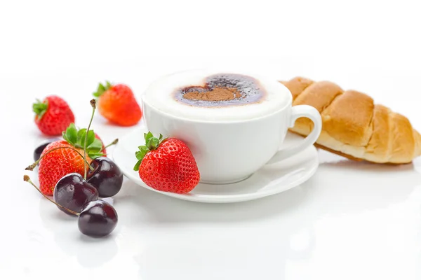 Cappuccino in einer Tasse in Herzform, Kirsche, Croissant und — Stockfoto