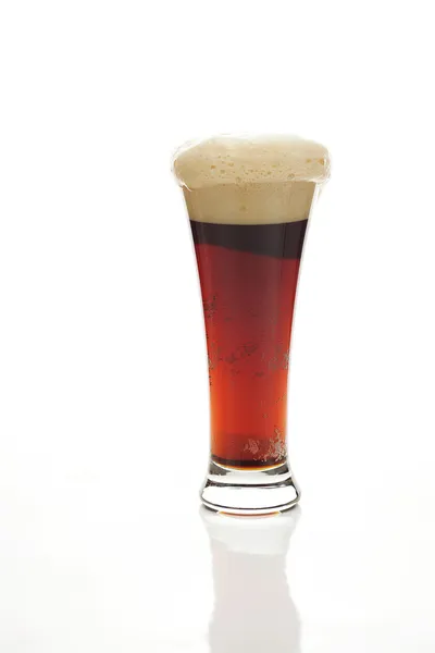 Темное пиво с пеной в высоком стакане, изолированном на белом — стоковое фото