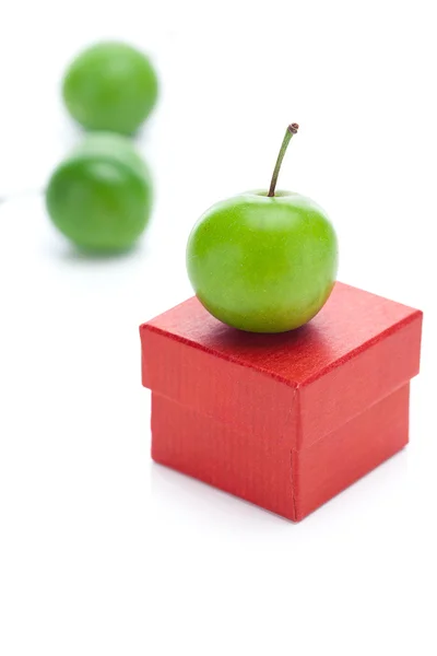 Rode geschenk doos en groene pruim geïsoleerd op wit — Stockfoto