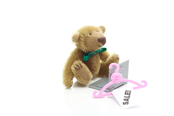 Urso de pelúcia, cabide com uma venda de etiqueta de preço e laptop em miniatura é — Fotografia de Stock