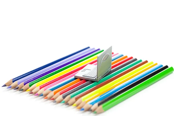 Matite colorate e laptop in miniatura isolato su bianco — Foto Stock