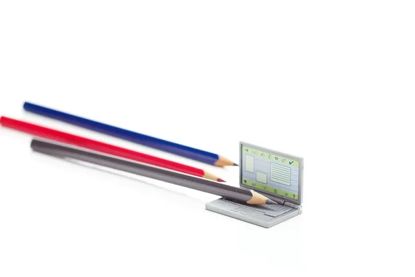 Renkli kalemler ve minyatür laptop üzerinde beyaz izole — Stok fotoğraf