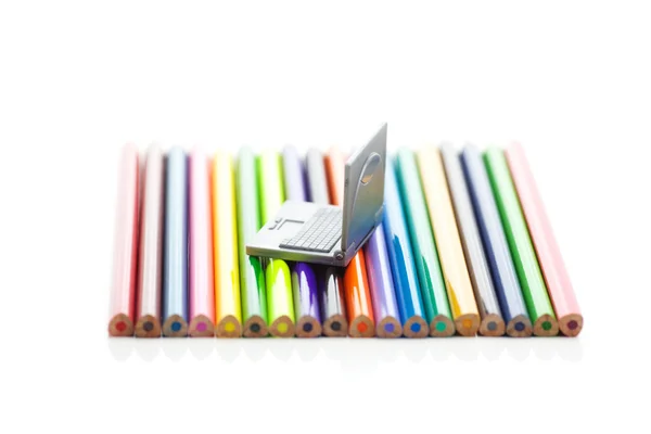 Színes ceruzák és elszigetelt fehér mini laptop — Stock Fotó