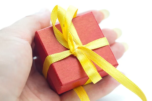 Confezione regalo rossa con un nastro giallo in mano alle donne — Foto Stock