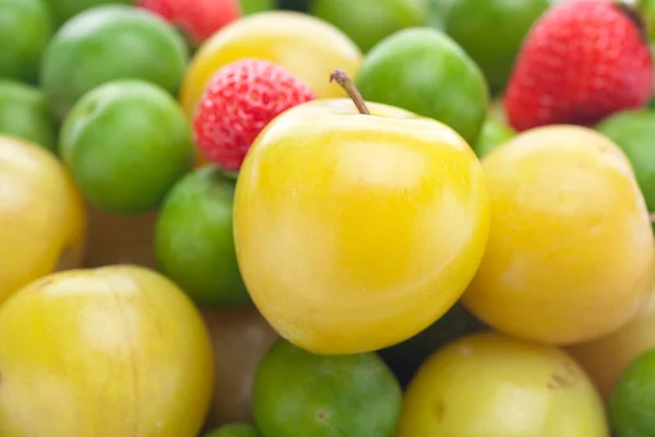 Bakgrunden jordgubb, gröna och gula plommon — Stockfoto