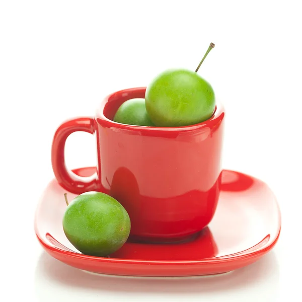 Groene pruim in de rode cup geïsoleerd op wit — Stockfoto