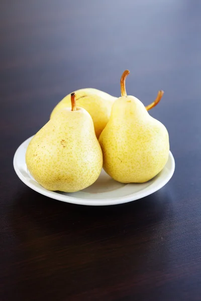 Pears on a plate on a wooden table — Stock Photo, Image