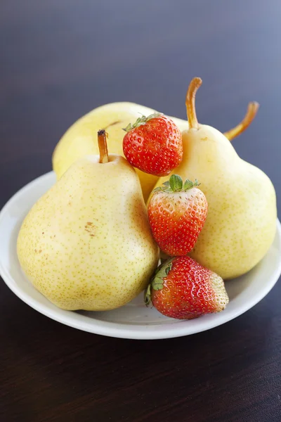 Strawberries and pears on a plate on a wooden table — Stock Photo, Image