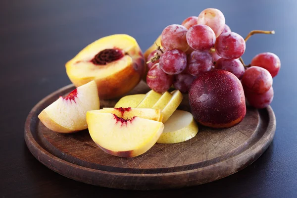 Melocotón, pera y uvas en una tabla de cortar — Foto de Stock