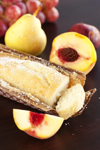 Fersken, pære, plomme, kokosnøttkake og druer på et trebord – stockfoto