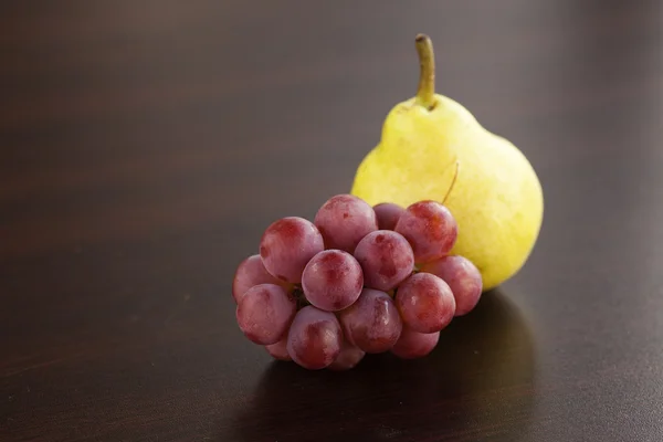 Pera y uvas tumbadas sobre una mesa de madera —  Fotos de Stock