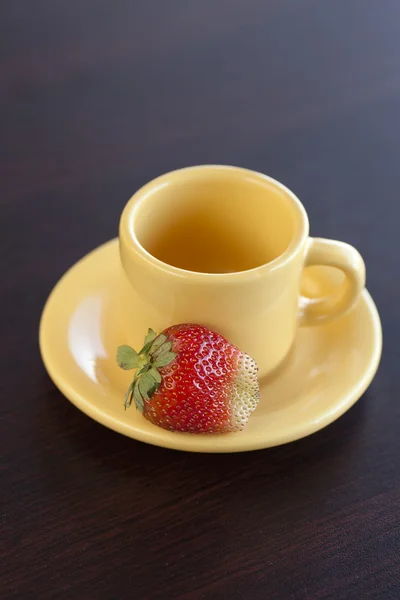 Strawberries and a cup with saucer on a wooden table — Stock Photo, Image