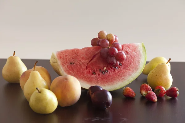 Vattenmelon, jordgubbar, druva, plommon och päron liggande på en trä t — Stockfoto