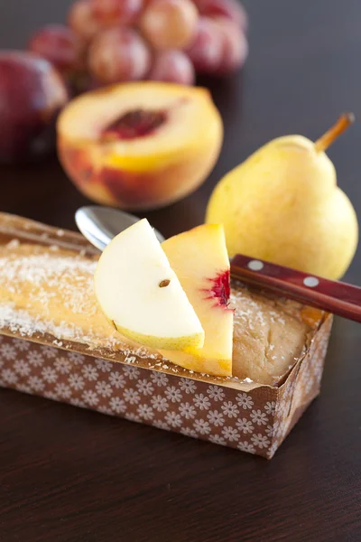 Persika, päron, plommon, kokos kaka, sked och druvor på en trä flik — Stockfoto
