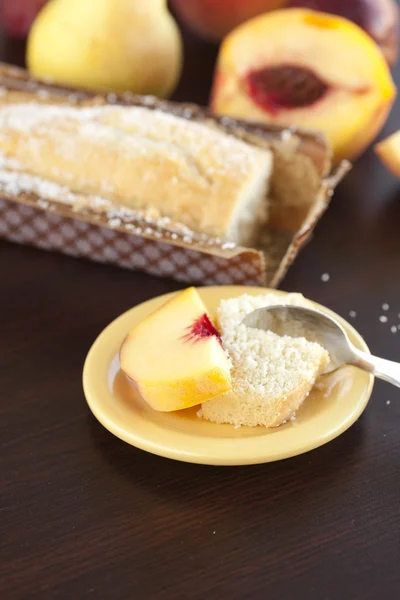 Peach, pear, plum, coconut cake and spoon on a wooden table — Stock Photo, Image