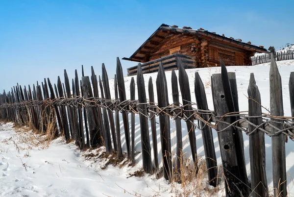 Старый зимний коттедж с забором — стоковое фото