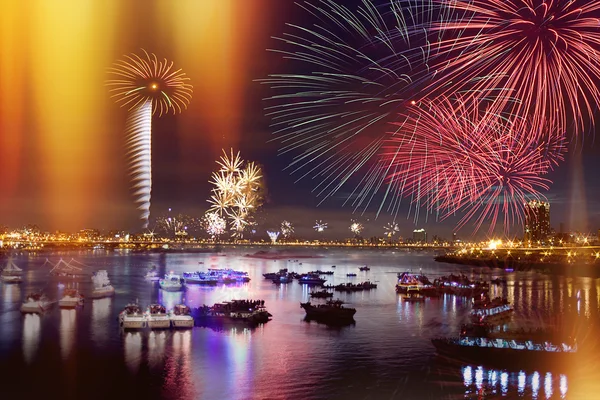 Fireworks firing up into the sky with a boat on a river below them, with a — Stock Photo, Image