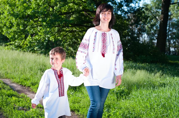 Mother and son in traditional ukrainian shirt walk on the meadow — Stock Photo, Image