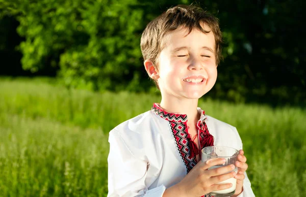 Oekraïense jongetje drinkt melk buitenshuis — Stockfoto
