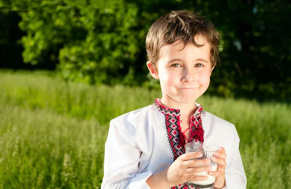 Oekraïense jongetje drinkt melk buitenshuis — Stockfoto