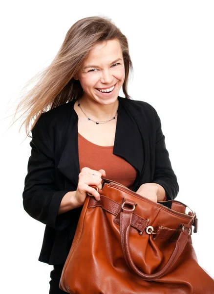 Молодая улыбающаяся женщина ищет в большой коричневой сумочке — стоковое фото
