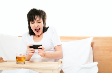 kadın yatakta cep telefonunda video oyunları oynuyor.