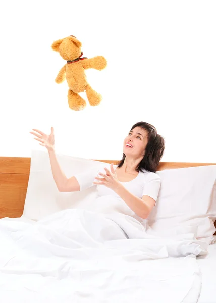 Woman in bed throwing teddy bear — Stock Photo, Image