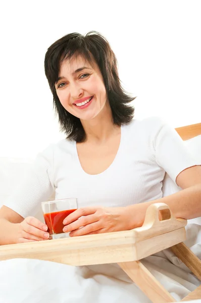 Mujer feliz en la cama con jugo de tomate —  Fotos de Stock