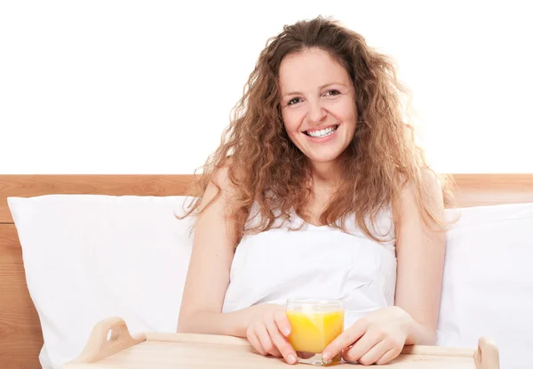 Bardak portakal suyu ile yatakta mutlu Kızıl saçlı kadın — Stok fotoğraf
