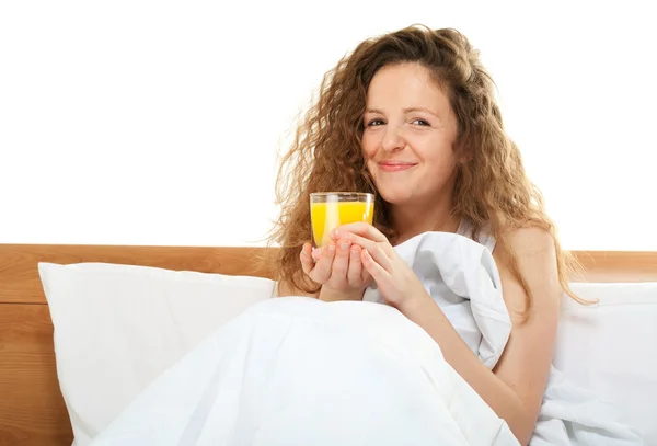 Mujer pelirroja feliz en la cama con un vaso de jugo de naranja — Foto de Stock