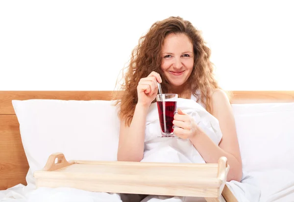 Pembe çay bardak ile yatakta mutlu Kızıl saçlı kadın — Stok fotoğraf