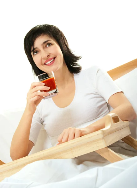 Mujer feliz en la cama con jugo de tomate —  Fotos de Stock