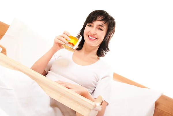 Elma suyu ile yatakta mutlu bir kadın — Stok fotoğraf
