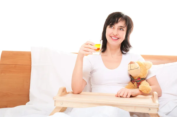 Happy dreamy woman in bed with apple juice and teddy bear — Stock Photo, Image