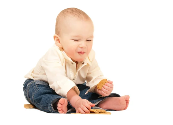 Счастливый смеющийся ребенок в джинсах ест крекер — стоковое фото