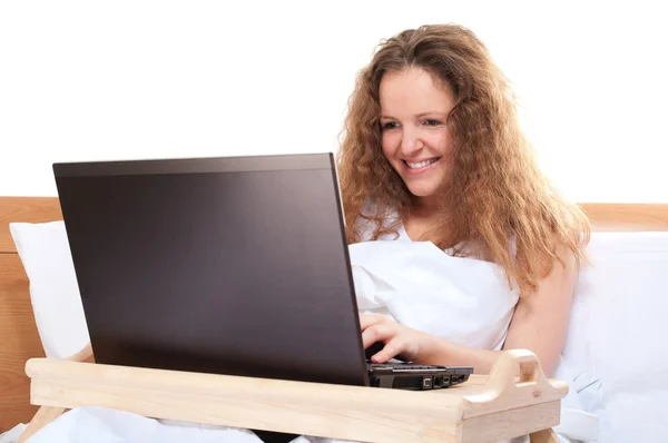Donna con computer portatile a letto — Foto Stock