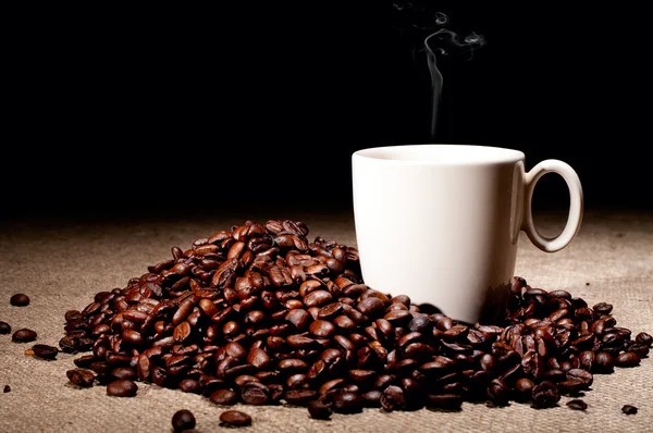 Kaffeebohnen und Tasse auf Jute — Stockfoto