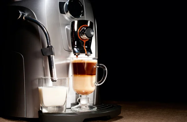 Koffiemachine met melkglas en cappuccino Stockafbeelding