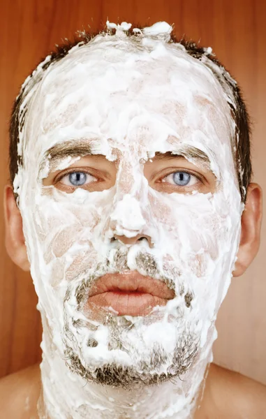 Человек со сливками для бритья на лице — стоковое фото