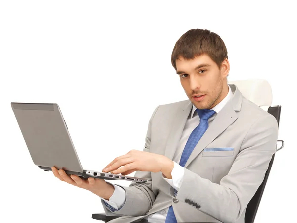 Joven hombre de negocios sentado en silla con portátil Imagen de stock