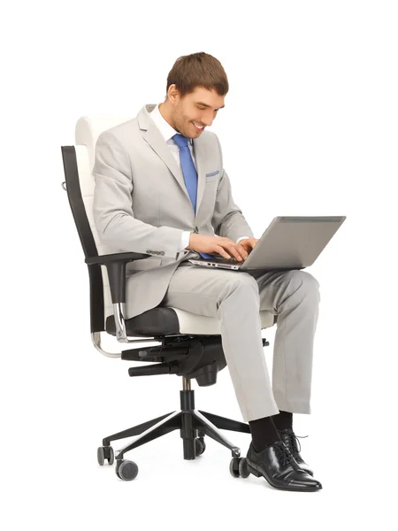 Mladý podnikatel, sedí v křesle s notebookem — Stock fotografie