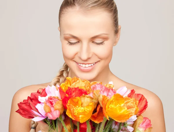 Härlig kvinna med röda blommor — Stockfoto