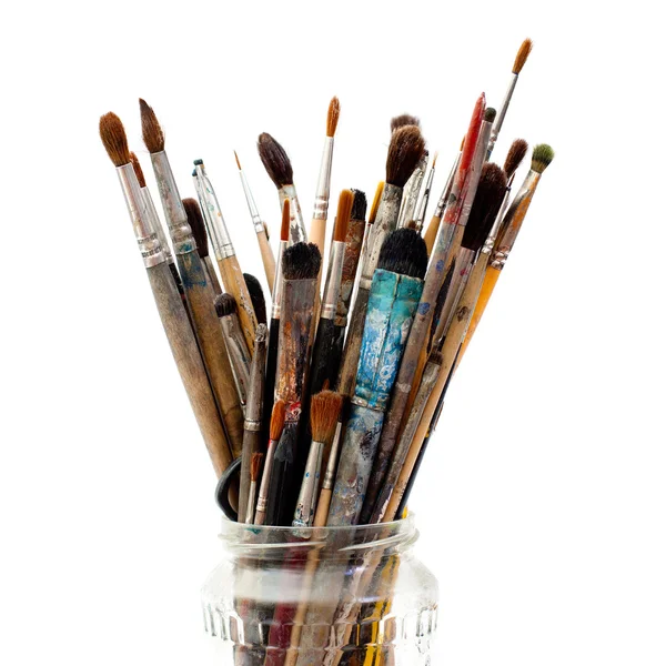 Assorted dirty painting brushes in glass flask — Stock Photo, Image