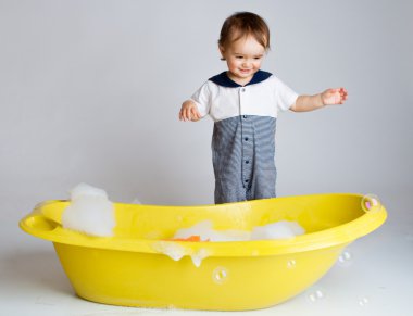 Charming baby standing near bathtub clipart