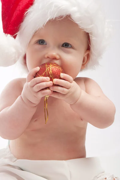 Baby eating red Xmas ball — Stock Photo, Image